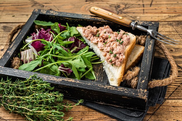 Tonijnsalade Sandwich met kaas, sla en rucola. Houten achtergrond. Bovenaanzicht.