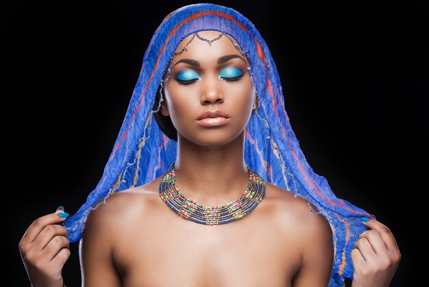 Too beautiful to be true. Beautiful African woman covering head by scarf and keeping eyes closed 