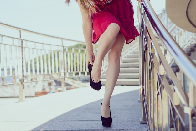 Too big small red short clothing  undress luxury elegant concept. close up photo of sexy exhausted tired lady taking off putting on shoes resting relaxing busy day party celebration time concept