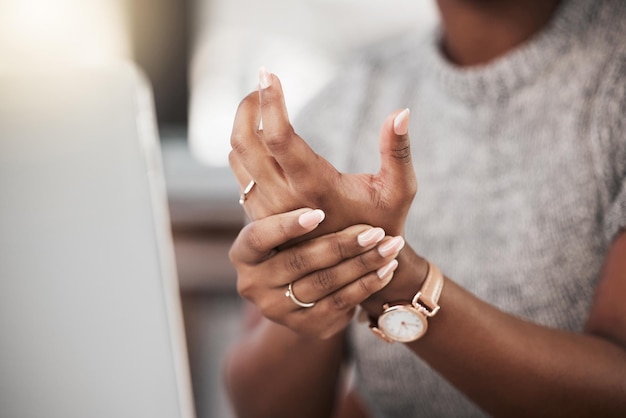 Too much typing is taking its toll Shot of a businesswoman experiencing wrist pain while using a laptop in a modern office