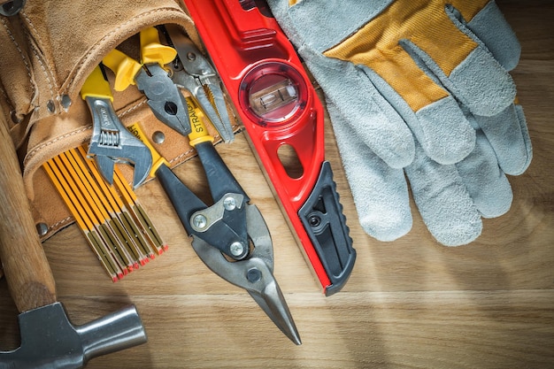 Пояс для инструментов с защитными перчатками на строительном уровне на деревянной доске