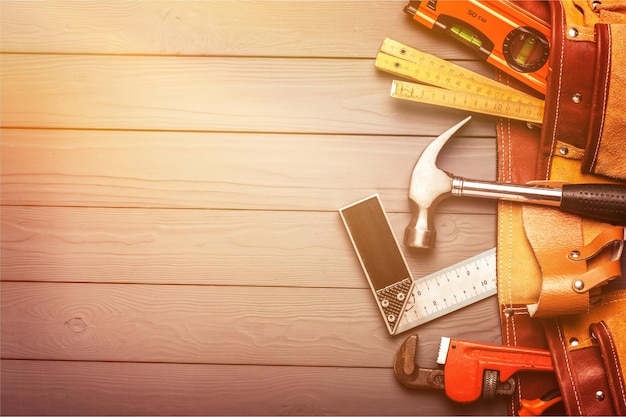 Tool belt with tools on wooden background