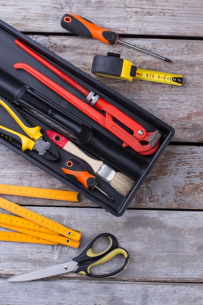 Tool box with different tools on wooden background