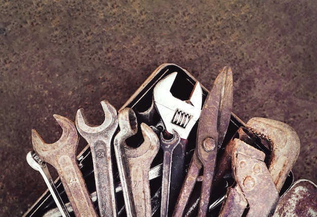 Toolbox with old vintage garage tools on rust metal\
background