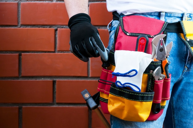 Tools in the belt for tools. The builder holds a screwdriver. 