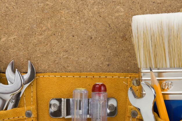 Tools in belt on wood background