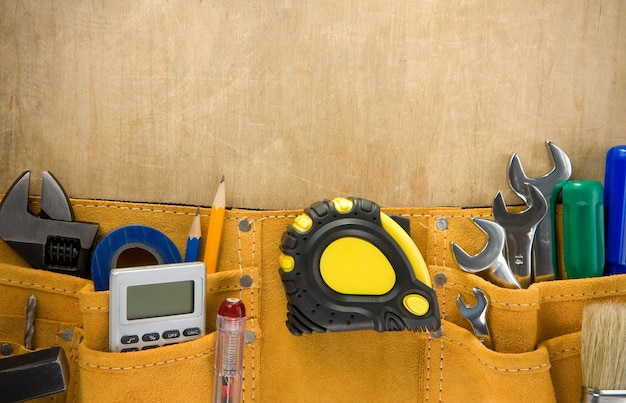 Tools in construction belt on wooden texture