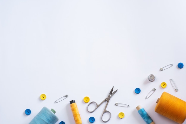 Tools for cutting and sewing. Seamstress kit. Multi-colored reels of threads, tape, needles on a white background