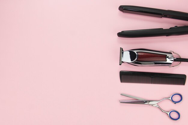 Tools for cutting and styling hair on a pink background