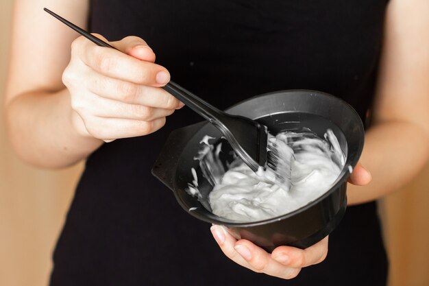 Tools for hair dyeing in woman hands. Colouring of hair at home