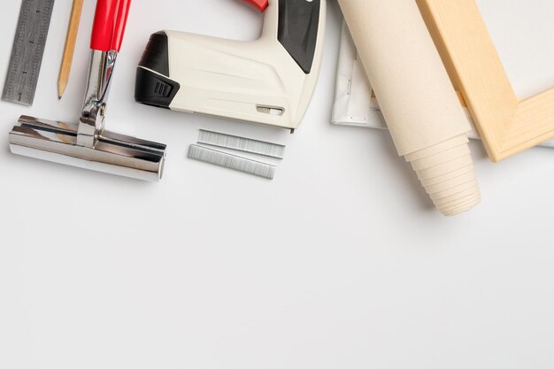 Tools for stretching canvas on a wooden frame in the frame
workshop on a white background the business of printing photos on
canvas copy space