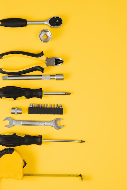 Tools top view on yellow background. Plier, open wrenches, screwdrivers and staple gun flat lay with copy space.