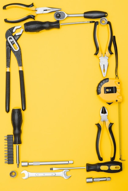 Tools top view on yellow background. Plier, open wrenches, screwdrivers and staple gun flat lay with copy space.