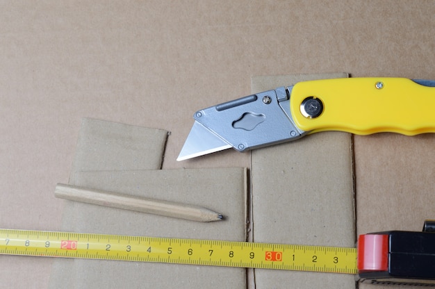 Tools for working with cardboard laid out on a table with cardboard scraps.