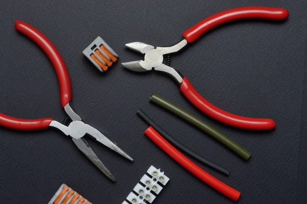 tools for working with electricity, terminal blocks and heat shrink tubes lie on a dark background.