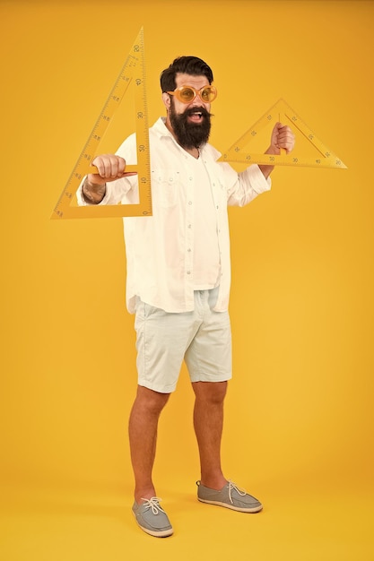 Photo tools you need for your drawing geometry or technical drawing teacher bearded man holding drawing instruments on yellow background engineer using triangles for making engineering drawing