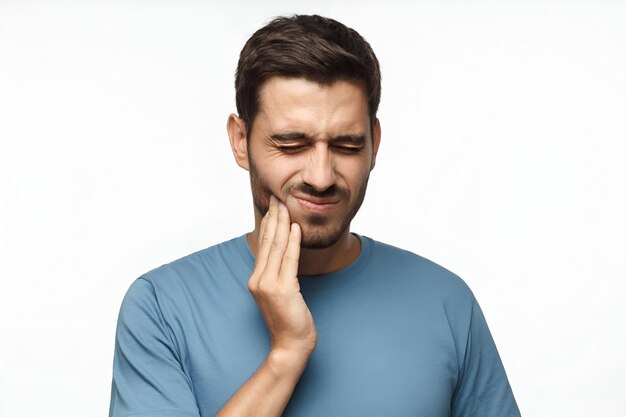 Foto concept di mal di dente scatto interno di un giovane maschio che sente il dolore tenendosi la guancia con la mano soffrendo di un forte mal di denti