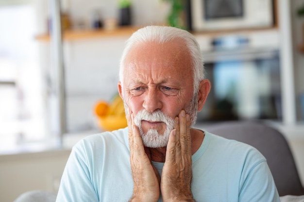 歯の痛みと歯科 ひどい強い歯の痛みに苦しんでいる年配の男性手で頬に触れる痛みを伴う歯痛歯科医療と健康の概念