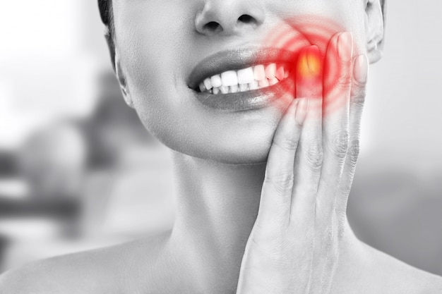 치아 통증과 치과. 젊은 여자 손으로 뺨을 만지고 강한 치아 통증에서 고통. 고통스러운 치통을 느끼는 여성. 치과 치료 개념