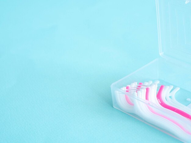 Зубная нить с пластиковой зубочисткой в прозрачном пластиковом контейнере на синем с местом для