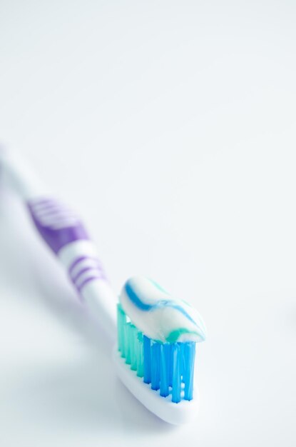 Toothbrush and applied toothpaste on white background