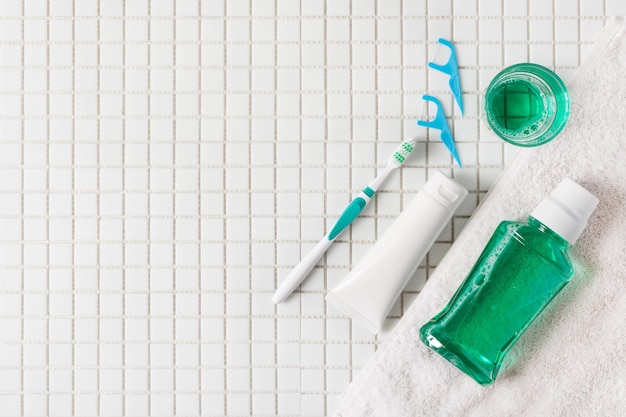 Spazzolino da denti filo interdentale e risciacquo orale vista dall'alto su sfondo bianco mosaico concetto di igiene dentale