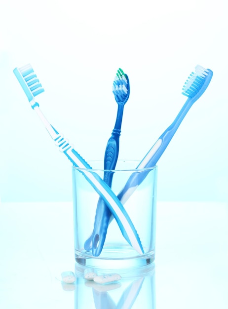 Toothbrush in glass and chewing gum on blue background