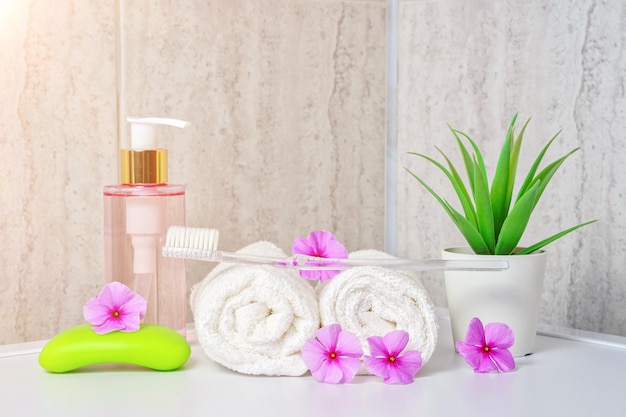 Toothbrush tonic for washing face and white towels pink flowers with copy space aromatherapy and ora...