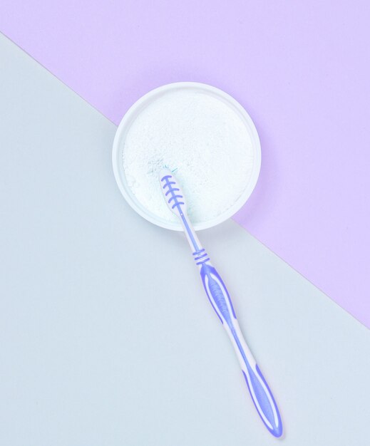 Toothbrush and tooth powder on a gray-purple paper background