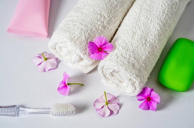 Toothbrush toothpaste and white towels pink flowers with soap aromatherapy and oral care body hygien...