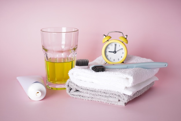 Photo toothbrush and towels with an alarm clock on pink