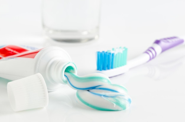 Toothbrush tube of toothpaste and a glass on a white background