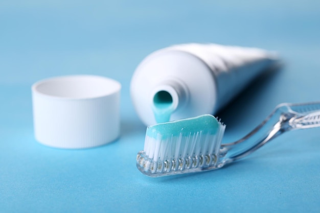 Toothbrush with blue toothpaste on color background