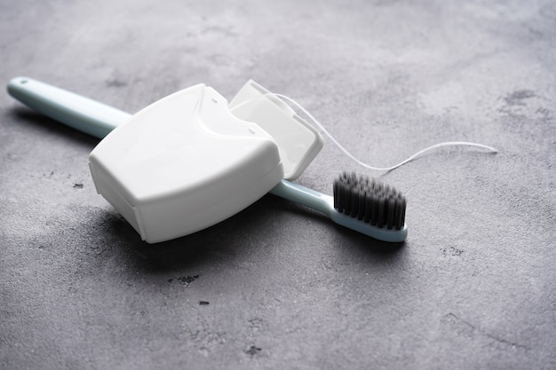 Toothbrush with dental floss on gray