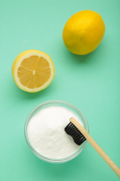 Photo toothbrush with lemon and baking soda on mint background vertical photo