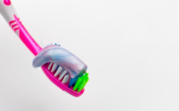 Зубная щетка с выжатой зубной пастой на белом фоне