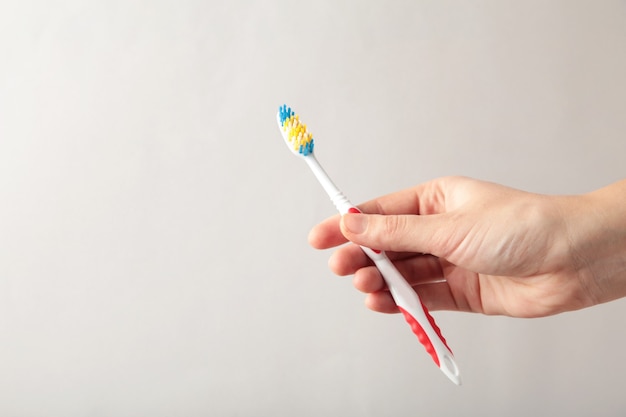 Toothbrush in woman's hand on grey isolated