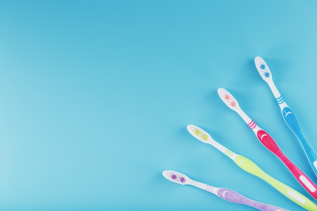 Toothbrushes of different colors in a row on a blue surface