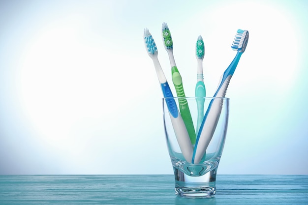 Toothbrushes in glass on color background