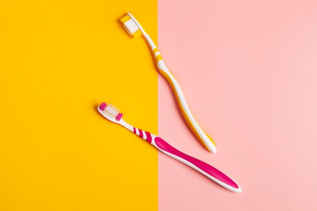 Toothbrushes in two colors yellow and pink 2 color background