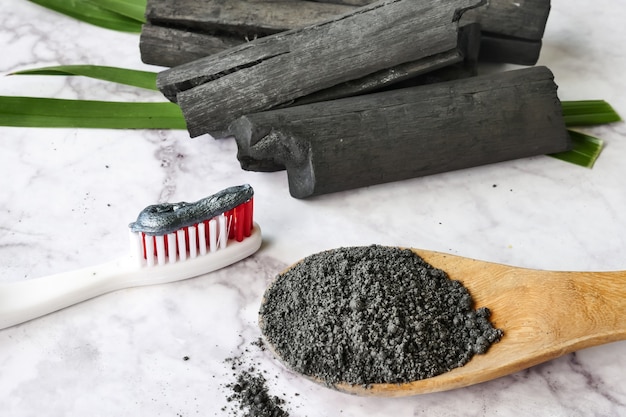 Toothpaste by activated charcoal powder on marble table