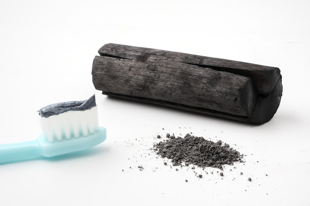 Toothpaste by activated charcoal powder on white background