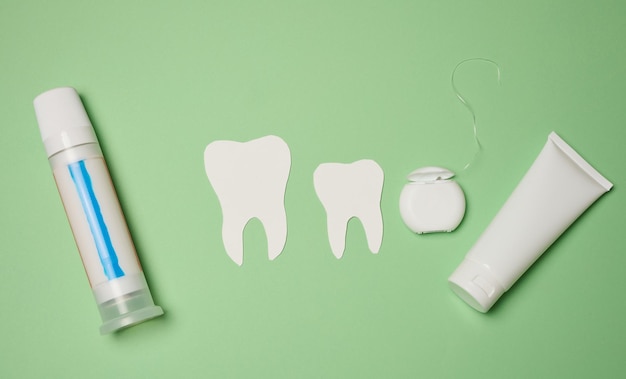 Toothpaste and dental floss on a green background top view