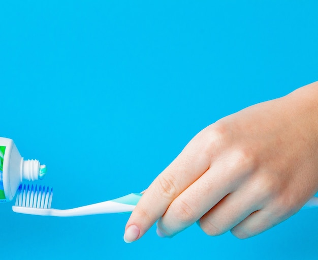 Зубная паста на крупном плане зубной щетки на синем светлом фоне.