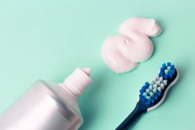 Toothpaste in tube and toothbrush on blue background. Dental hygiene concept.