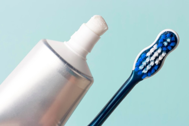 Toothpaste in tube and toothbrush on blue background. Dental hygiene concept.