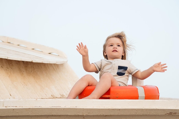 Top activities for toddler at beach. First vacation with child tips and advice. Boy little kid sit on lifebuoy. Toddler enjoy vacation at beach. Take care about safety while travel with child.