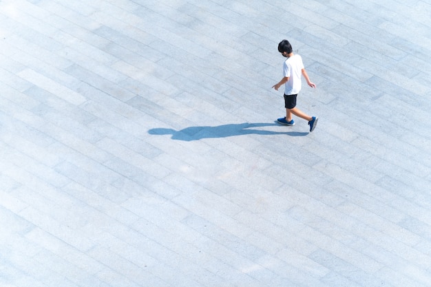 旅行や運動のために屋外の歩道橋を歩いている少年の空撮の上部