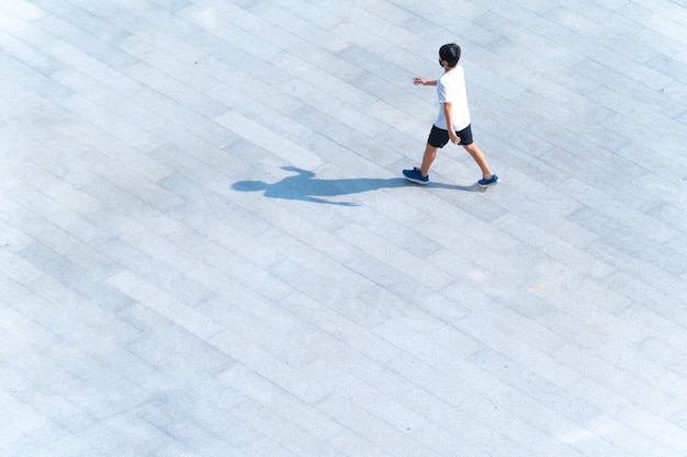 旅行や運動のために屋外の歩道橋を歩いている少年の空撮の上部