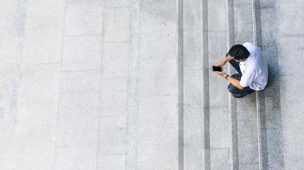 the top aerial view of the man in white shirt uses mobile phone 